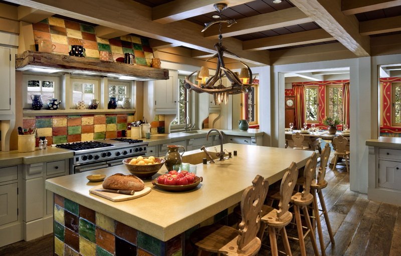 Деревенская кухня с большой островной поверхностью, декорированная цветной плиткой, которая служит ярким акцентом в помещение