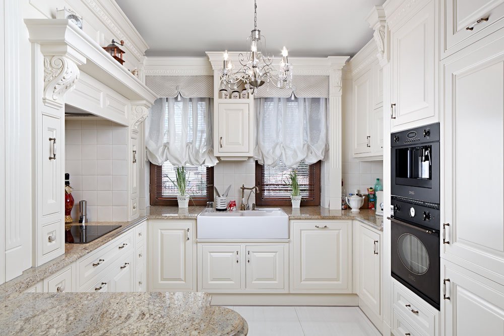 Белая кухня с шикарной люстрой посреди комнаты